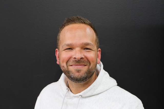 Smiling man in white hoodie that says Good energy on it