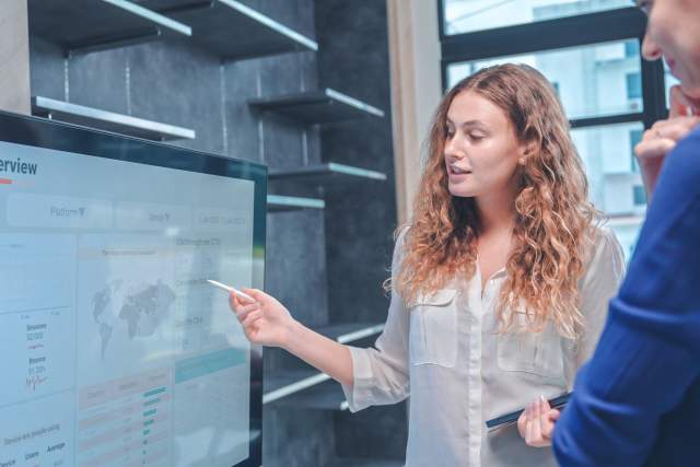 A woman with curly hair stands at a chart