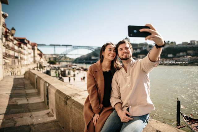 A young couple takes a selfie with a river in the background.