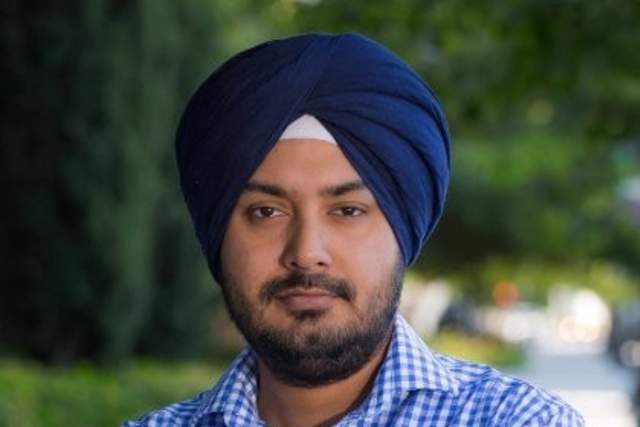 A bearded man wearing a turban and collared shirt