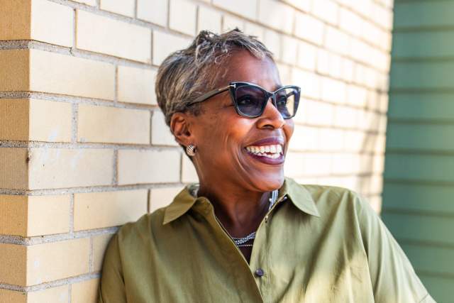 an image of cecelia gore laughing and looking off camera while leaning against a cream city brick wall