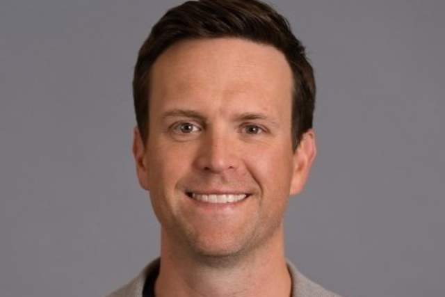 Smiling man in khaki suit jacket and black t-shirt