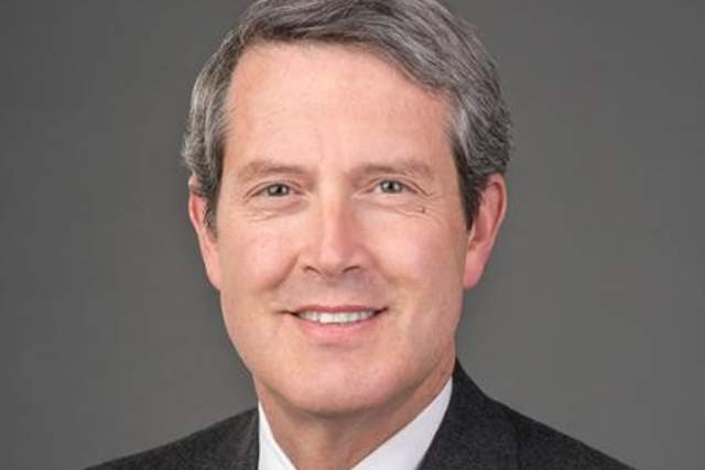 Smiling man in dark grey suit and red tie