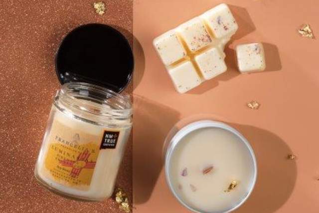 Image showing a white candle in a glass jar next to a white bowl with three vanilla-scented wax melts, on a beige background adorned with golden confetti.