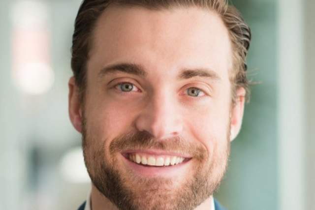 Smiling man with beard wearing a blue suit and collar shirt