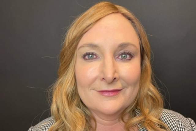 Half-smiling woman wearing a black and white houndstooth jacket and black blouse