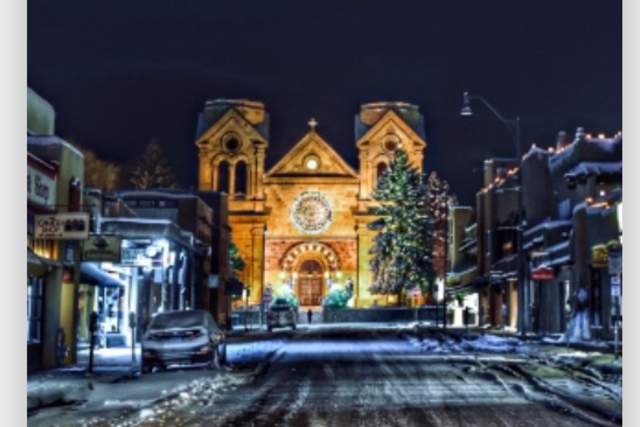 The cover of a calendar featuring The Cathedral Basilica of St. Francis of Assisi with snowy store fronts and trees in the foreground.