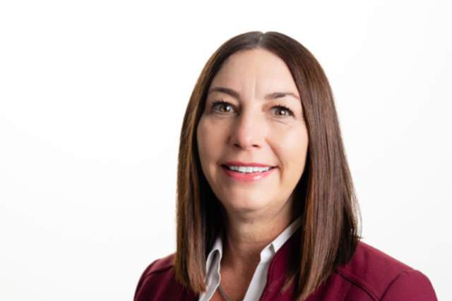 Smiling woman in burgandy suit coat and white button down shirt