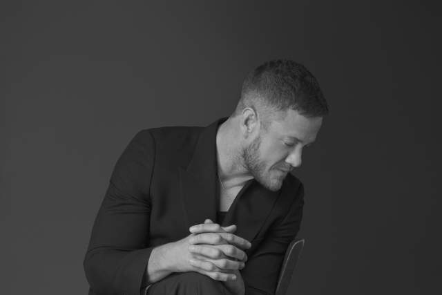 Dan Reynolds sitting sideways on a chair