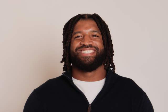 Smiling man in black half-zip and white t-shirt