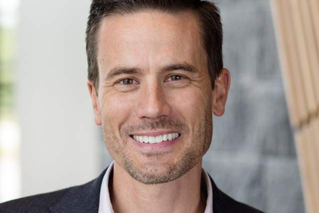 Smiling man in dark suit coat and button up shirt
