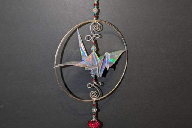 A hanging mobile with an origami crane and bell