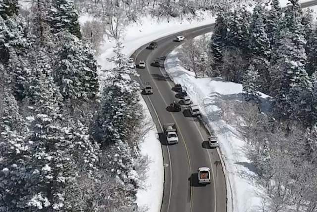 Cars driving on a slightly wet road in a snowy canyon