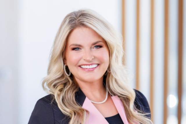 Smiling woman in dark grey blazer with pink lapel