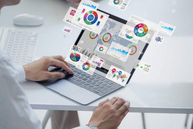 A person using a laptop with data dashboards, charts, and reports displayed on screen, representing CRM data analysis and ongoing data hygiene routines.