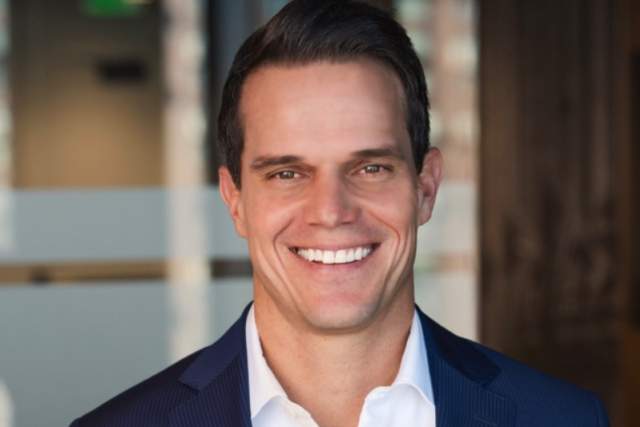 Smiling man in dark blue suit coat and white button down shirt