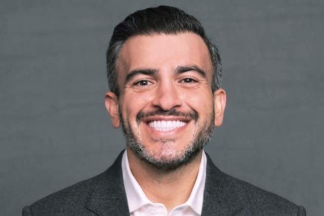 Smiling bearded man wearing a suit jacket and white shirt