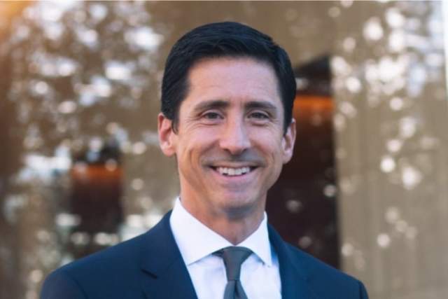 Smiling man in dark blue suit and grey tie
