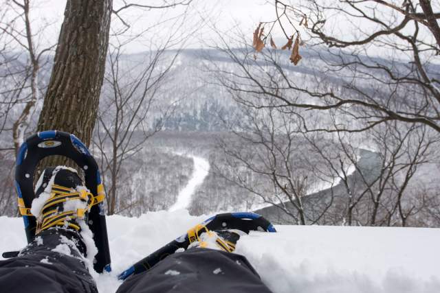 Booted feet in snowshoes overlooking a snow covered overlook