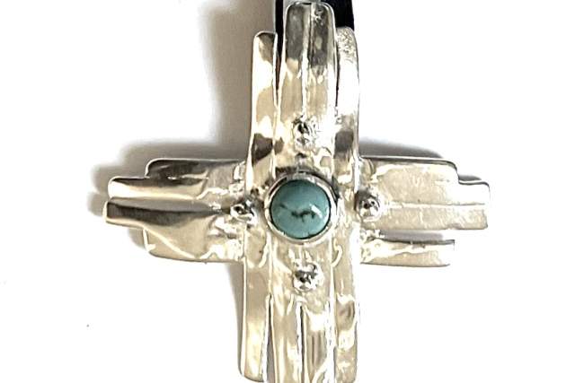 A sterling silver pendant in the shape of a Zia with a turquoise stone in the center