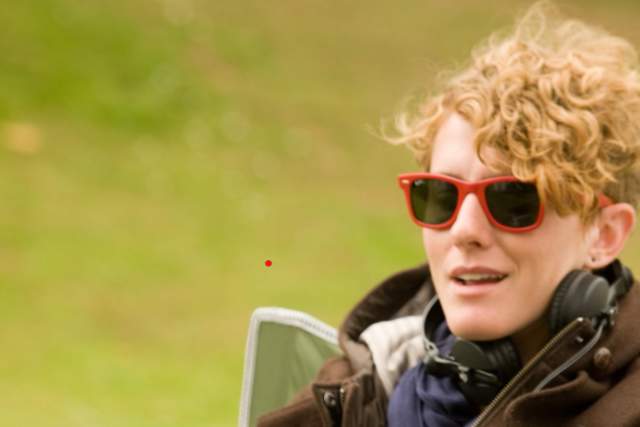 Woman in leather jacketand sunglasses leaning back in outdoor chair.