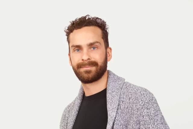 Bearded man in black t-shirt and cardigan sweater