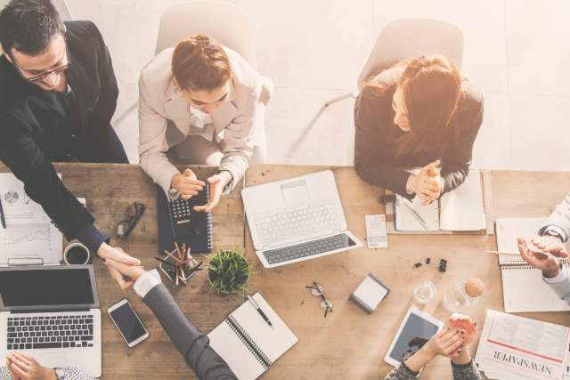 An aerial photo of people working at a conference table during a meeting.