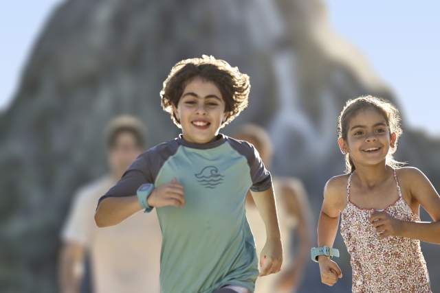 Kids in swim suits running ahead of their parents at Universal's Volcano Bay