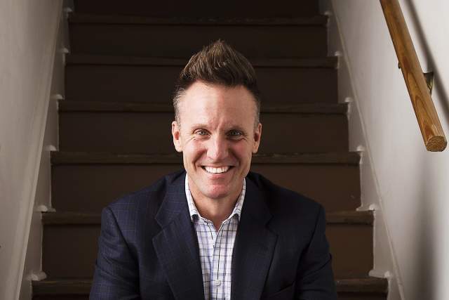 Happy man in suit coat and collared shirt sitting on the stairs