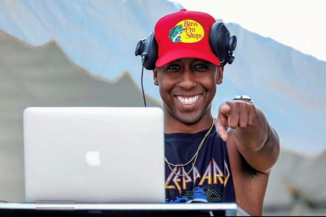 Michael Warren points at the camera and smiles while playing music from his laptop at Alabaster CityFest.