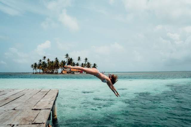 Mujer saltando al agua desde un muelle en la bahía de San Blas, Gunayala, Panamá.