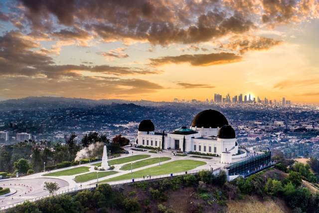 A wide shot of the Griffith Park Observatory overlooking Los Angeles at sunset.