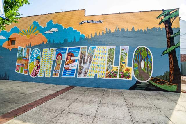 A mural in Montevallo of significant landmarks and historical stories painted into the word "Montevallo" with a sign overhead that says, "Make your mark."