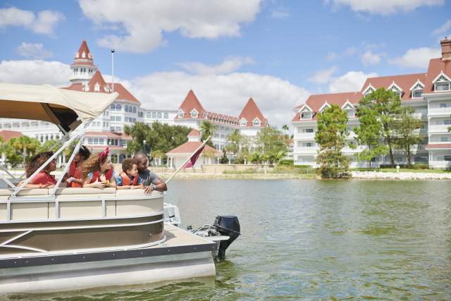 A family sails past Disney's Grand Floridian Resort on a pontoon boat rental from Walt Disney World Resort