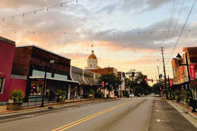 Downtown Columbiana Main Street shot from the road with string lights overhead and a sunset in the background.