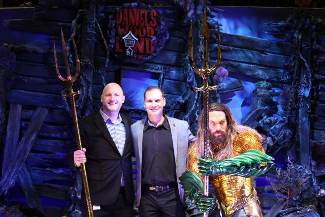 James Paulding and Andy Dautermann speak alongside Aquaman wax figure at IAAPA press conference.
