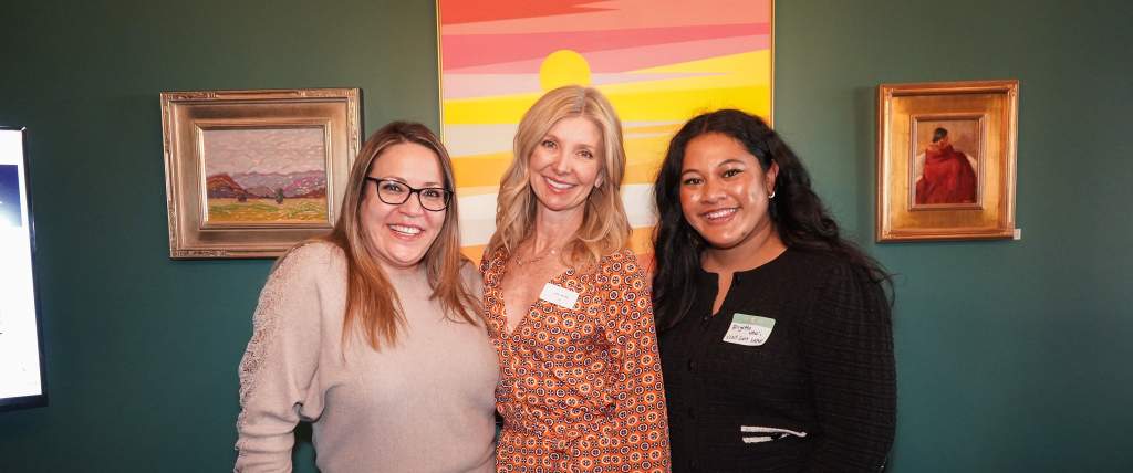 Three women standing close together and smiling
