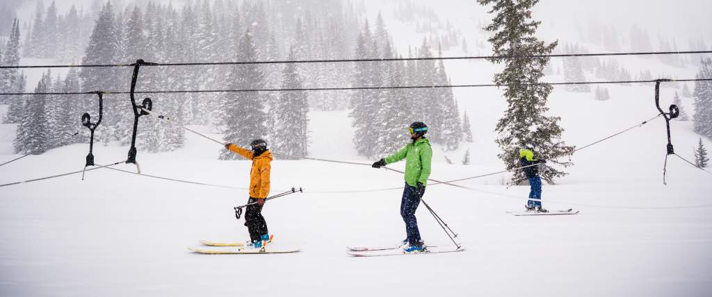 Two skiers on Alta's rope tow with chairlift lines in the background