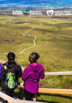 Group of walkers looking out over the landscape from the boardwalk at Cuilcagh Mountain.