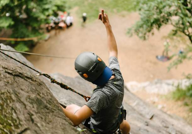 Man rock climbing on a cliff giving a thumbs up