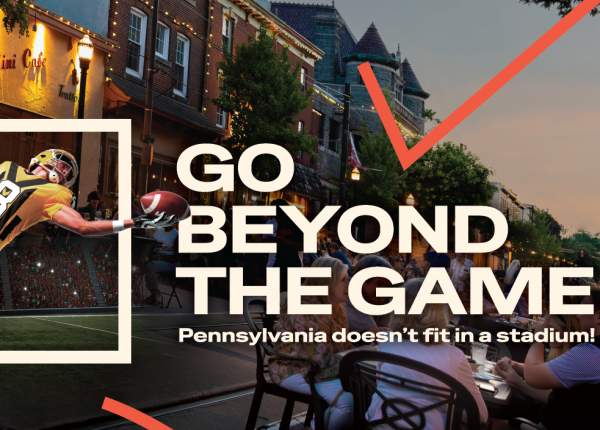 A football player jumping through a square box in front of people sitting on a main street at dusk. The text overlay reads Go Beyond the Game. Pennsylvania doesn't fit in a stadium.
