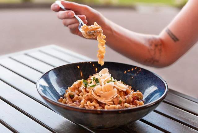 Fork lifting a bite of Carbonara topped with pancetta and shaved parmesan at 19 Okanagan Grill & Bar in West Kelowna