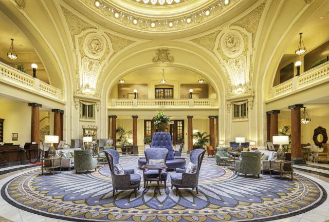 Ornate historical lobby with seating in the middle and a round skylight