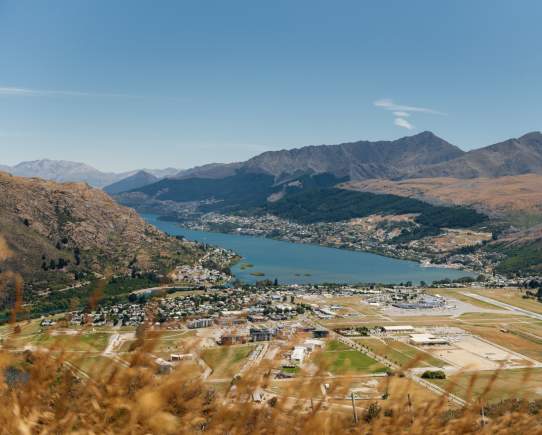 An aerial view of Queenstown Airport surrounded by Lake Whakatipu and mountains