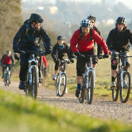 A group cycling on rented mountain bikes towards the off-road mountain biking trail at Ashton Court - credit Pedal Progression