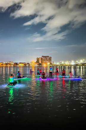 Paddleboarding at night near city with Epic Paddle Adventures