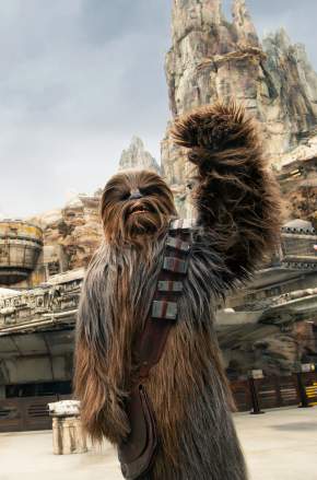 Disney's Hollywood Studios. Chewbacca waving at Star Wars: Galaxy’s Edge, with the Millennium Falcon and towering rock formations in the background.