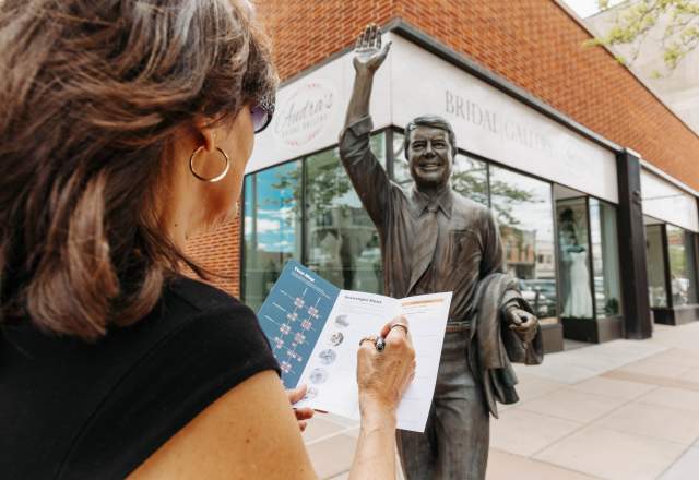 person filling out scavenger hunt in front of Jimmy Carter city of presidents statue in rapid city,sd
