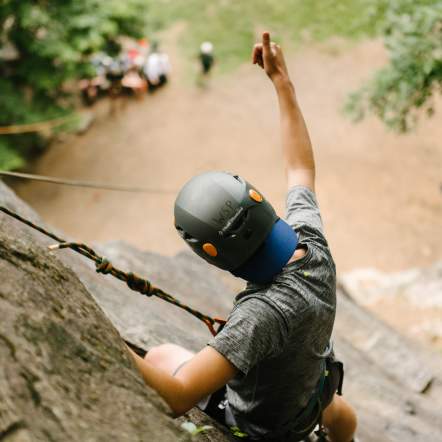 Man rock climbing on a cliff giving a thumbs up
