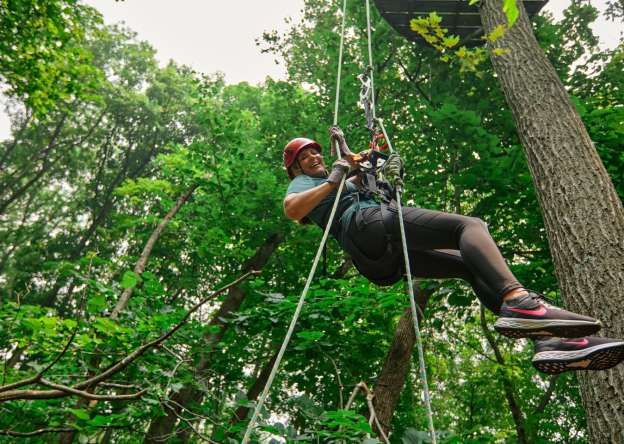 Person on a zip line in the woods.